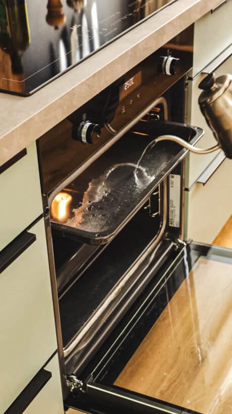 Wasser für Dampferzeugung auf Backblech gießen